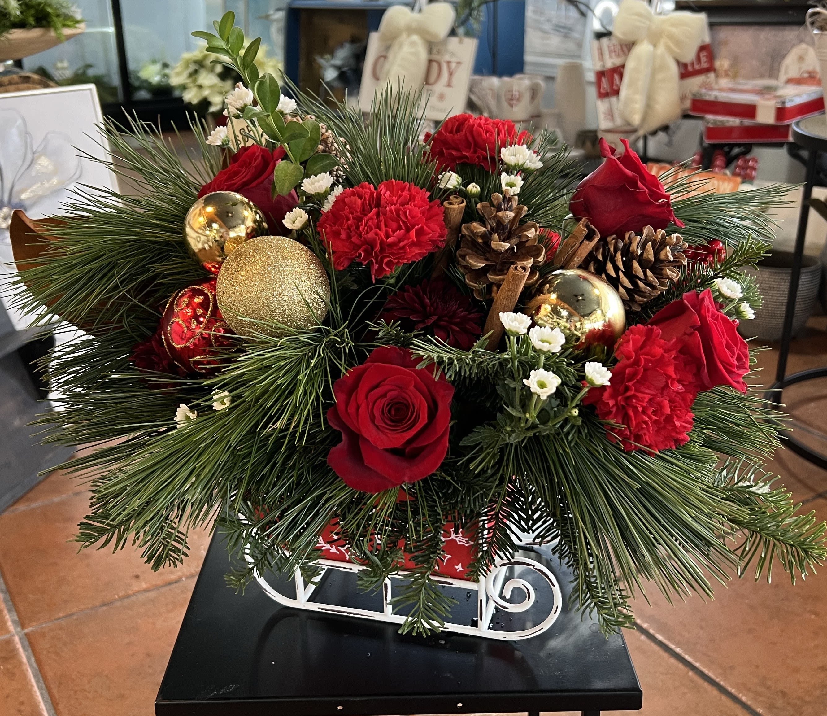 Christmas arrangement with red roses, carnations, pinecones, and gold ornaments