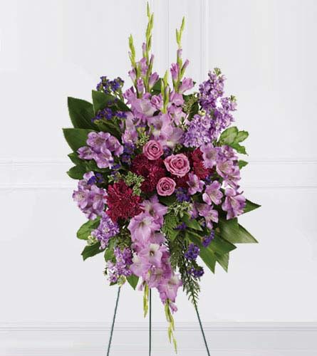 Standing spray of purple flowers with pink roses on a metal easel
