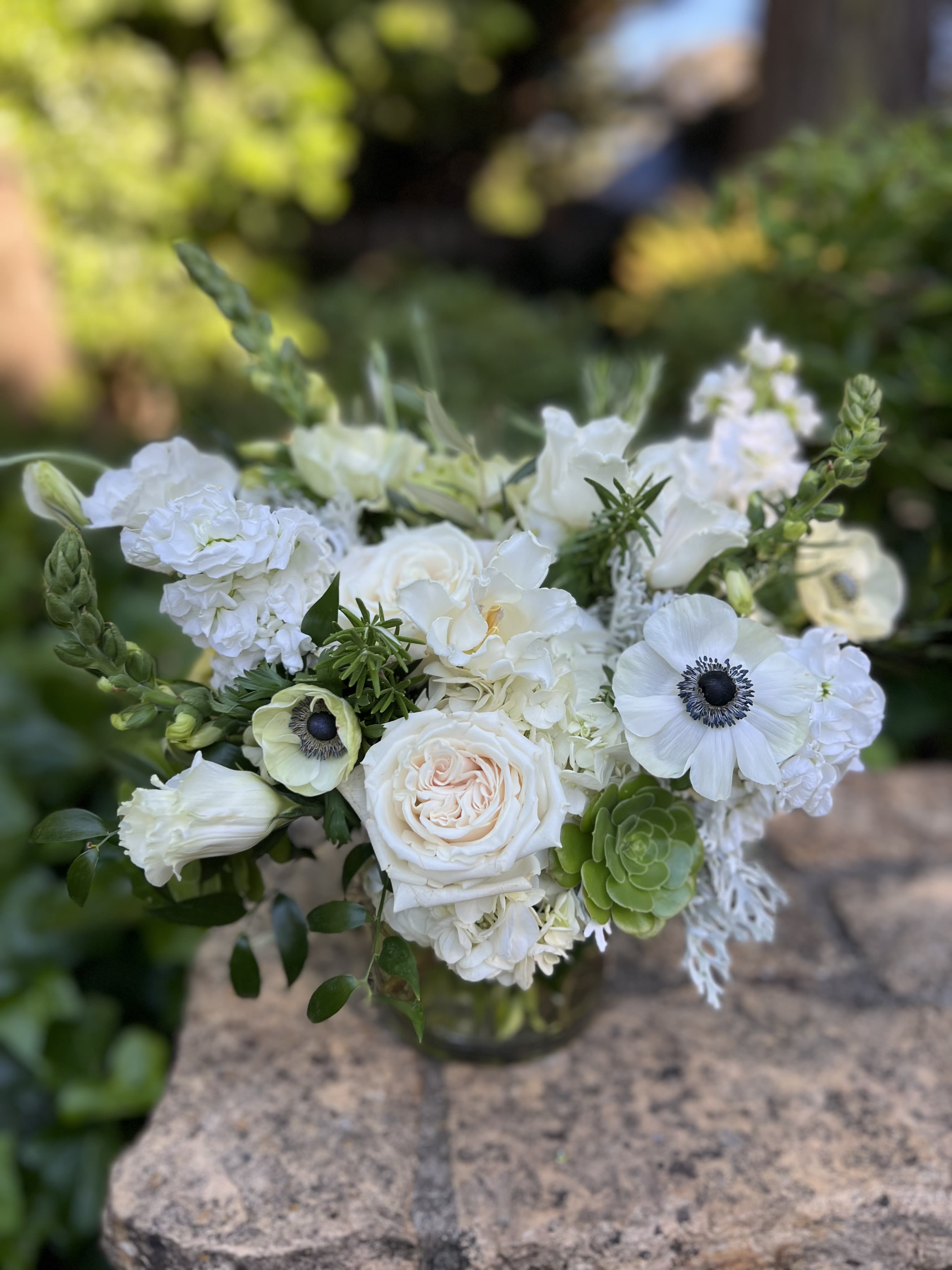 White floral bouquet in a glass vase with green accents