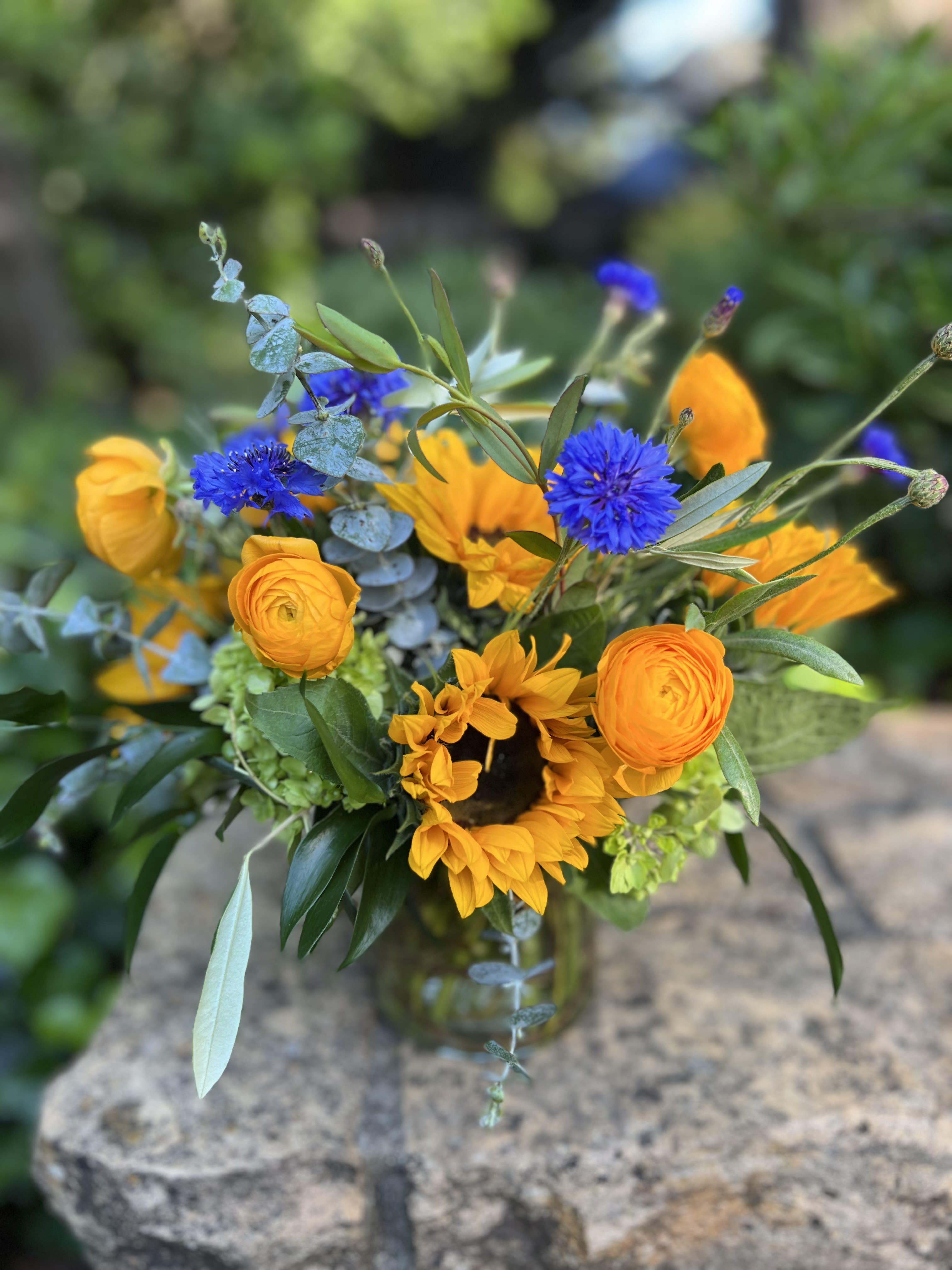 Bouquet of yellow sunflowers and blue flowers in a glass vase