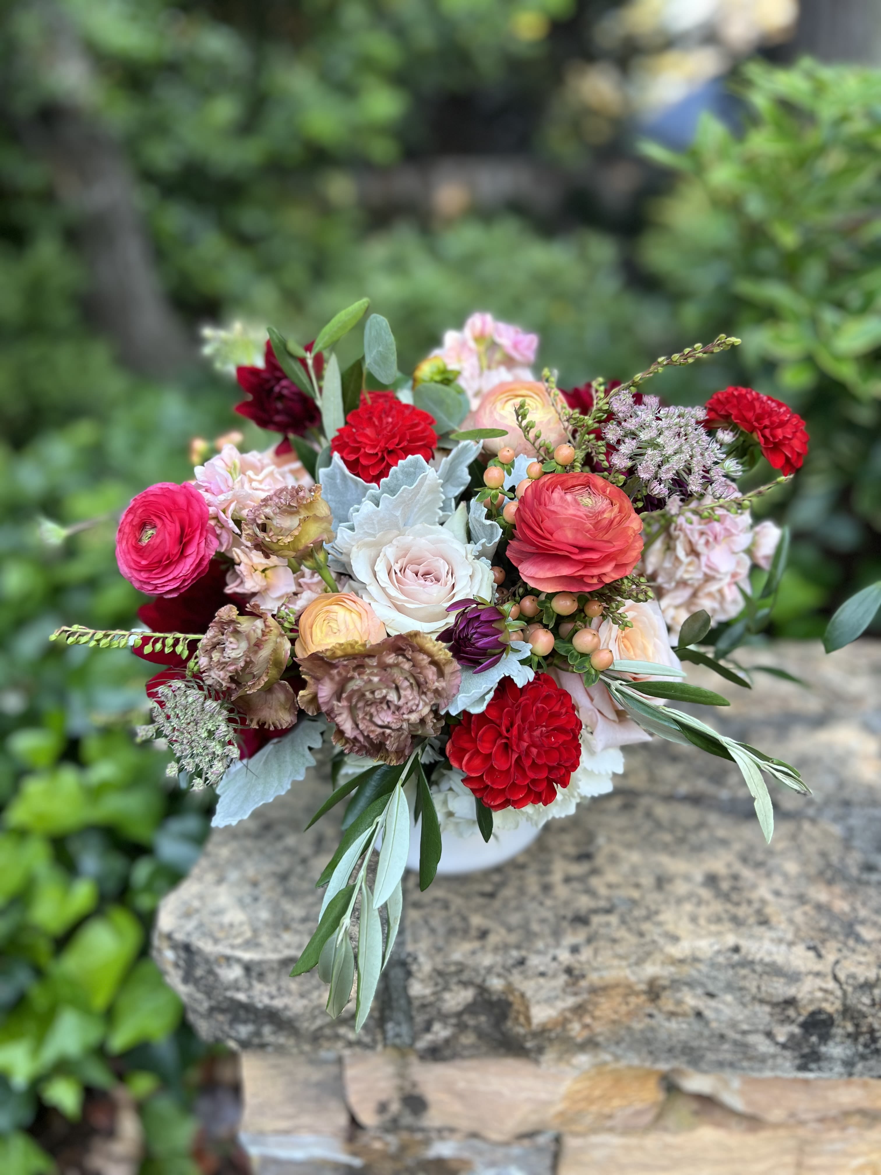 Mixed bouquet of pink, red, and white flowers in a low vase