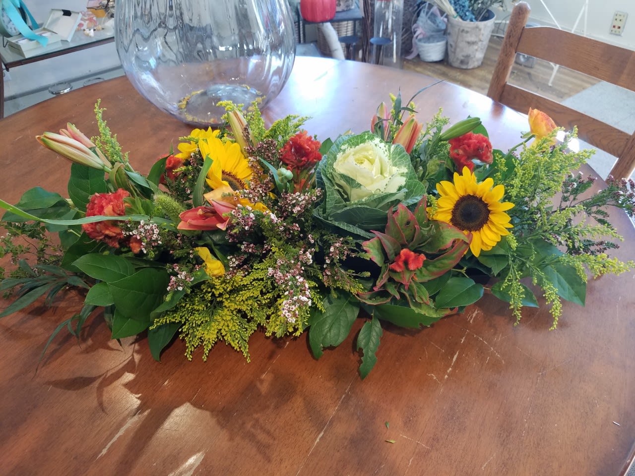Low floral centerpiece with sunflowers, roses, and lilies on a table