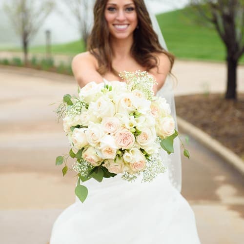 Bride holding a bouquet of white and blush roses