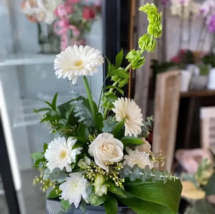 White gerbera daisies and a white rose in a vase with green accents