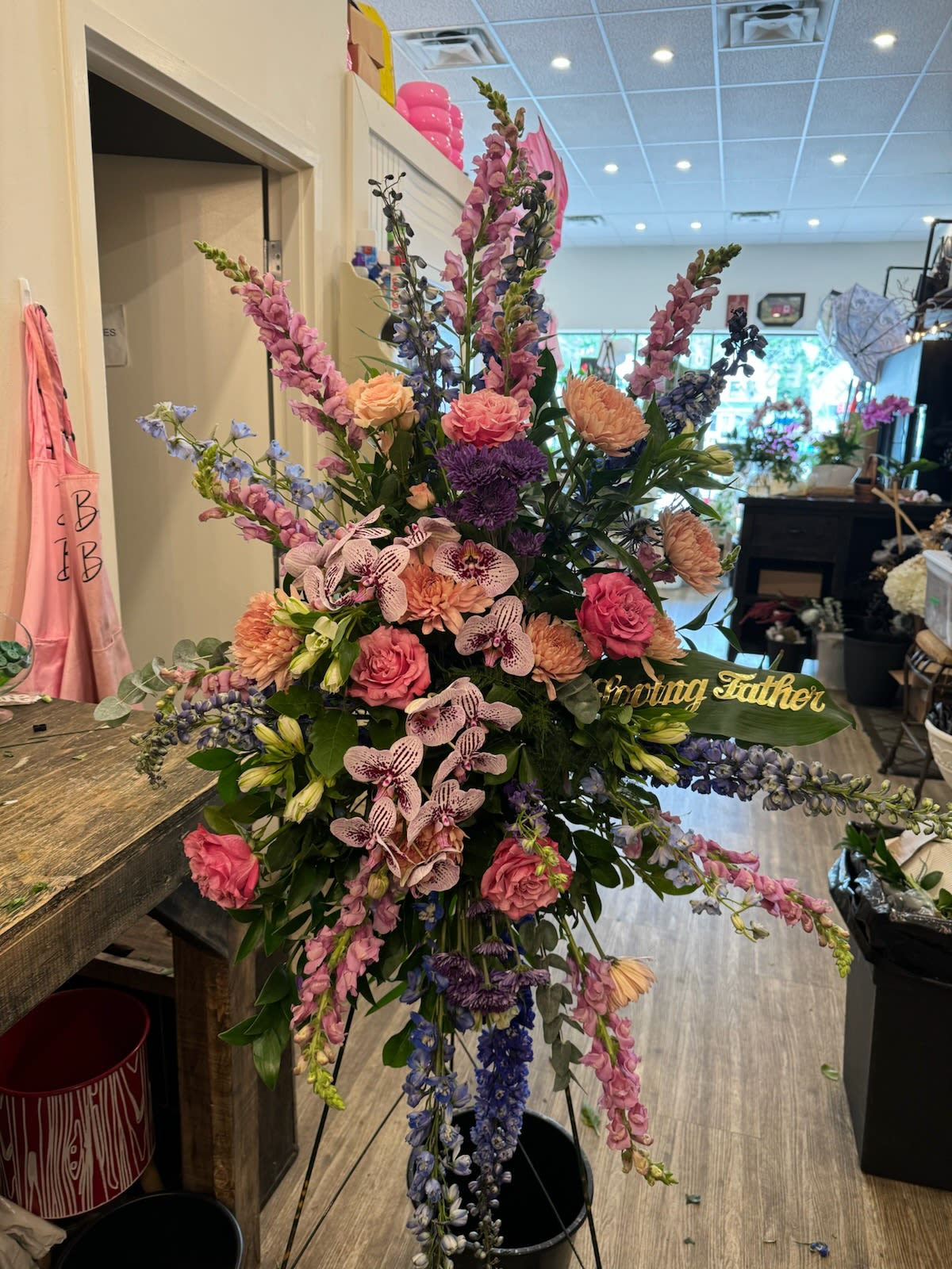 Tall floral standing spray with pink, purple, and peach blooms