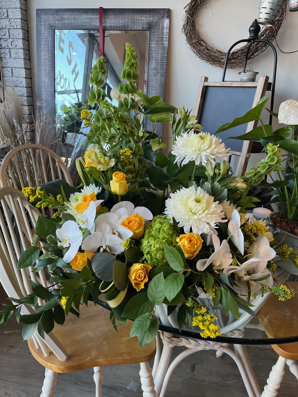 Large floral arrangement with white orchids, yellow roses, and white chrysanthemums