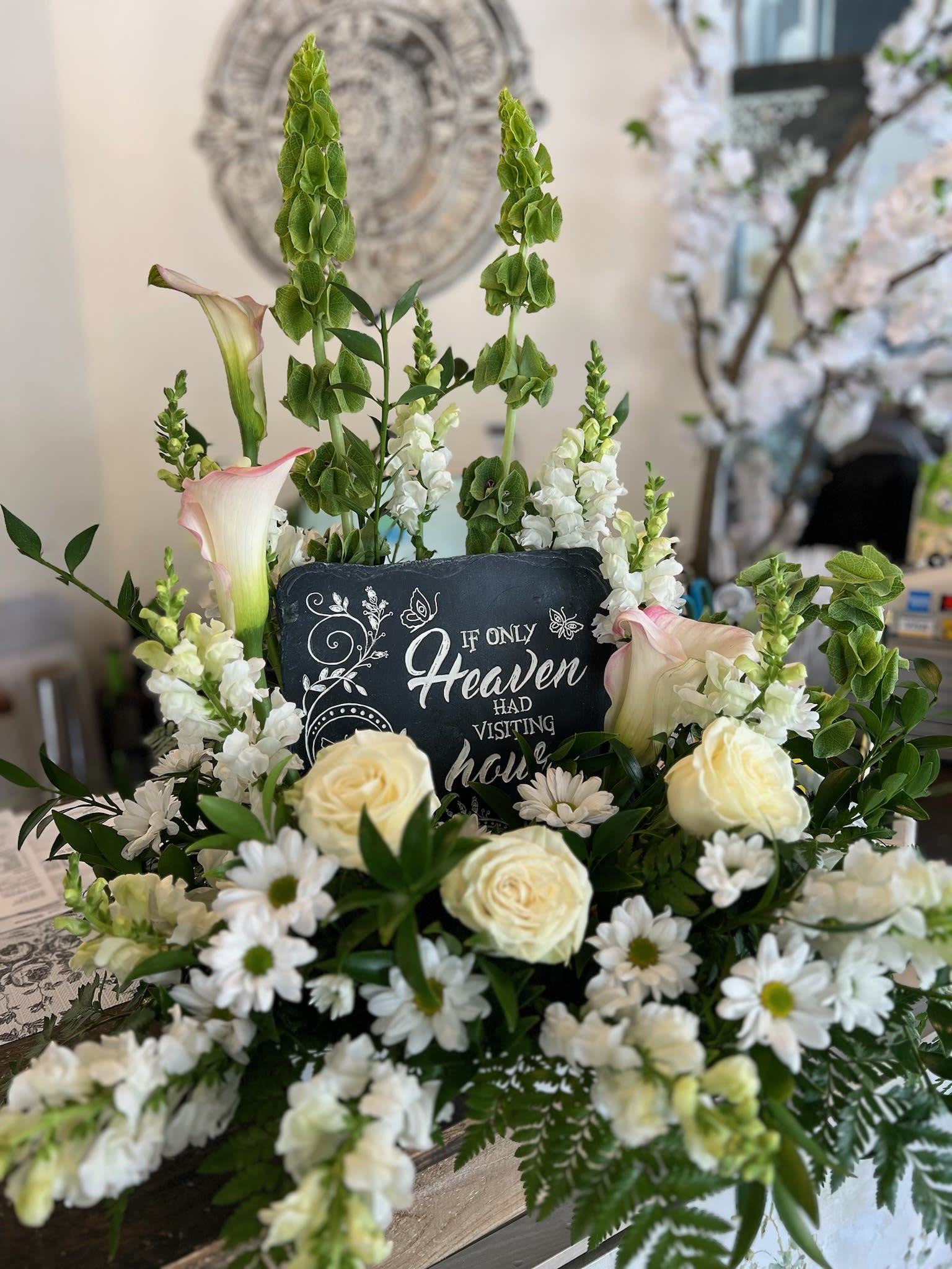 Sympathy floral arrangement with white flowers and a memorial sign