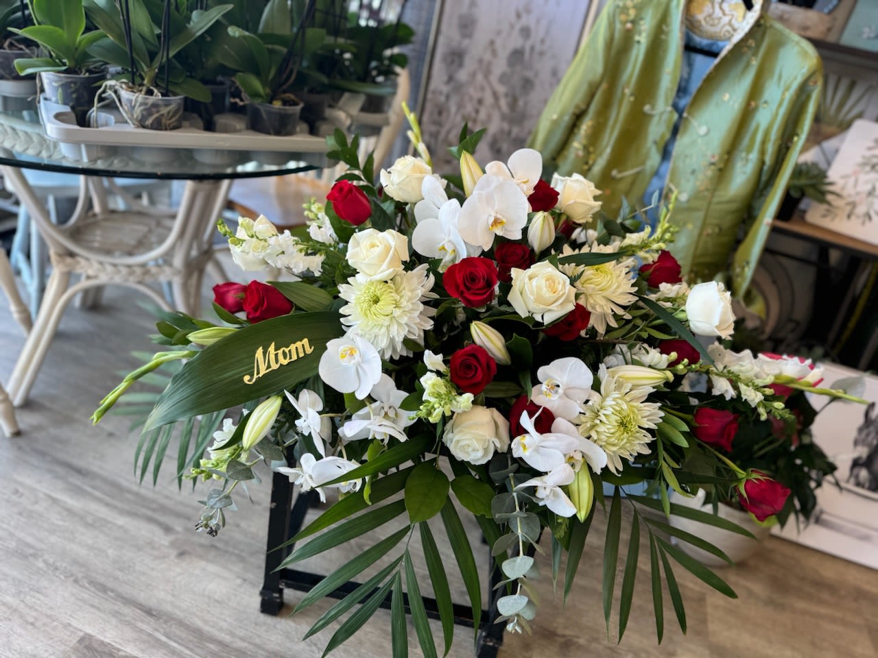 Red and white rose arrangement with orchids and mums in a black container