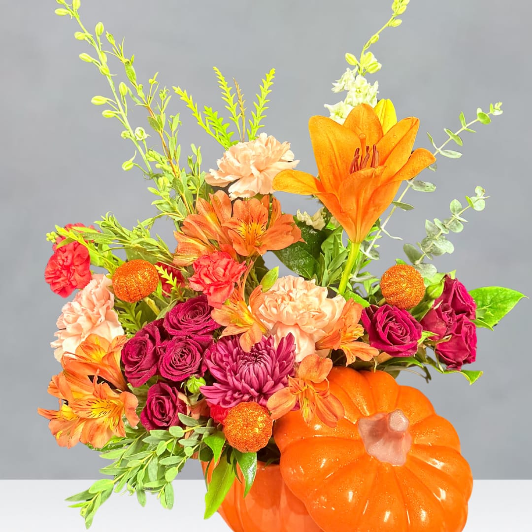 Orange pumpkin vase with mixed orange, pink, and purple flowers