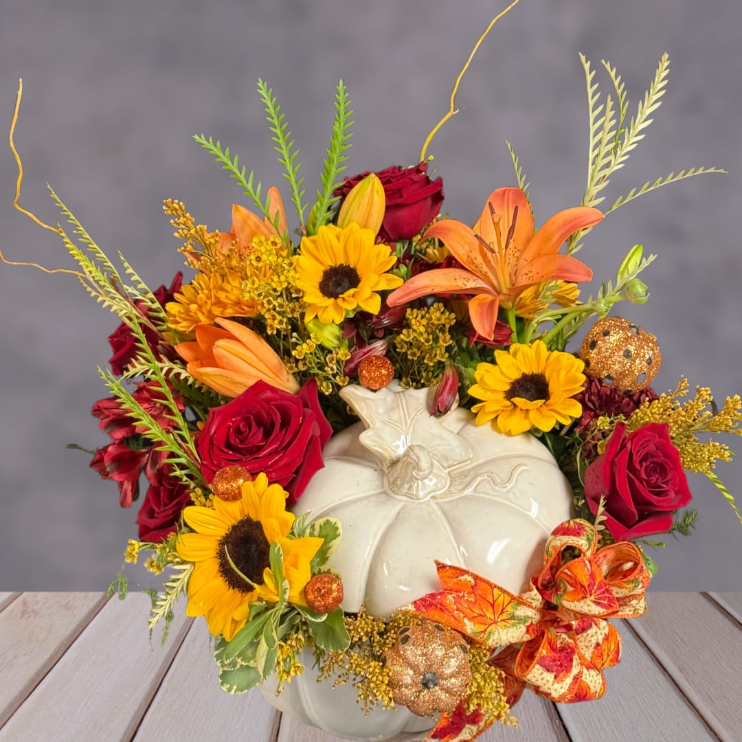 Fall floral arrangement in a white pumpkin vase with sunflowers, roses, and lilies