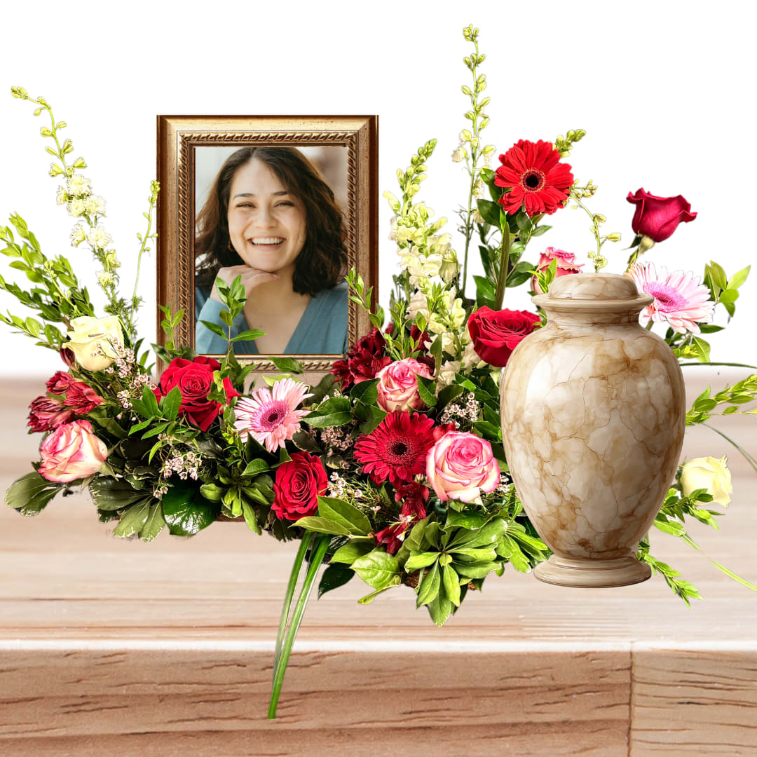 Floral tribute with a framed portrait and urn surrounded by red and pink roses