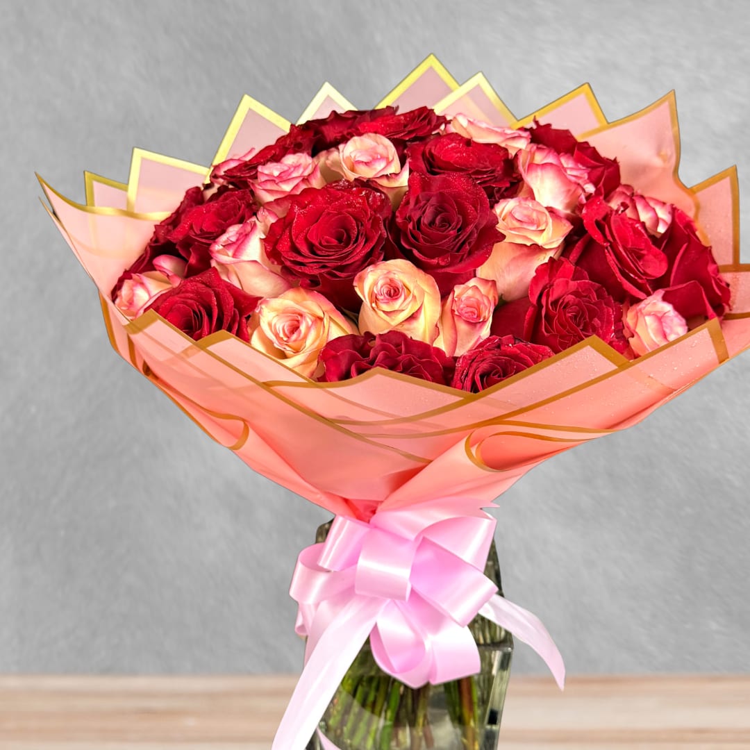 Bouquet of red and pink roses wrapped in pink paper with a ribbon
