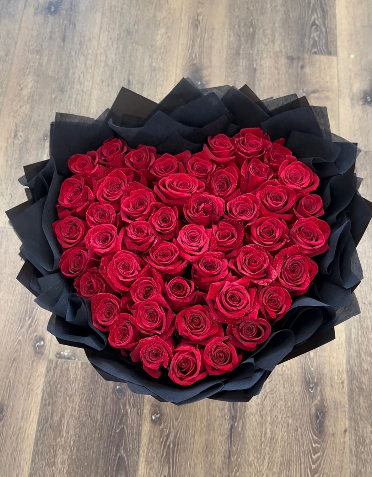 Corazon De Rosas Bouquet - Corazon De Rosas (Heart of roses) is a romantic bouquet of 50 red roses carefully arranged in the shape of a heart and wrapped in elegant black Korean-style paper. A bold and sophisticated gesture to say “I love you” without saying a word.