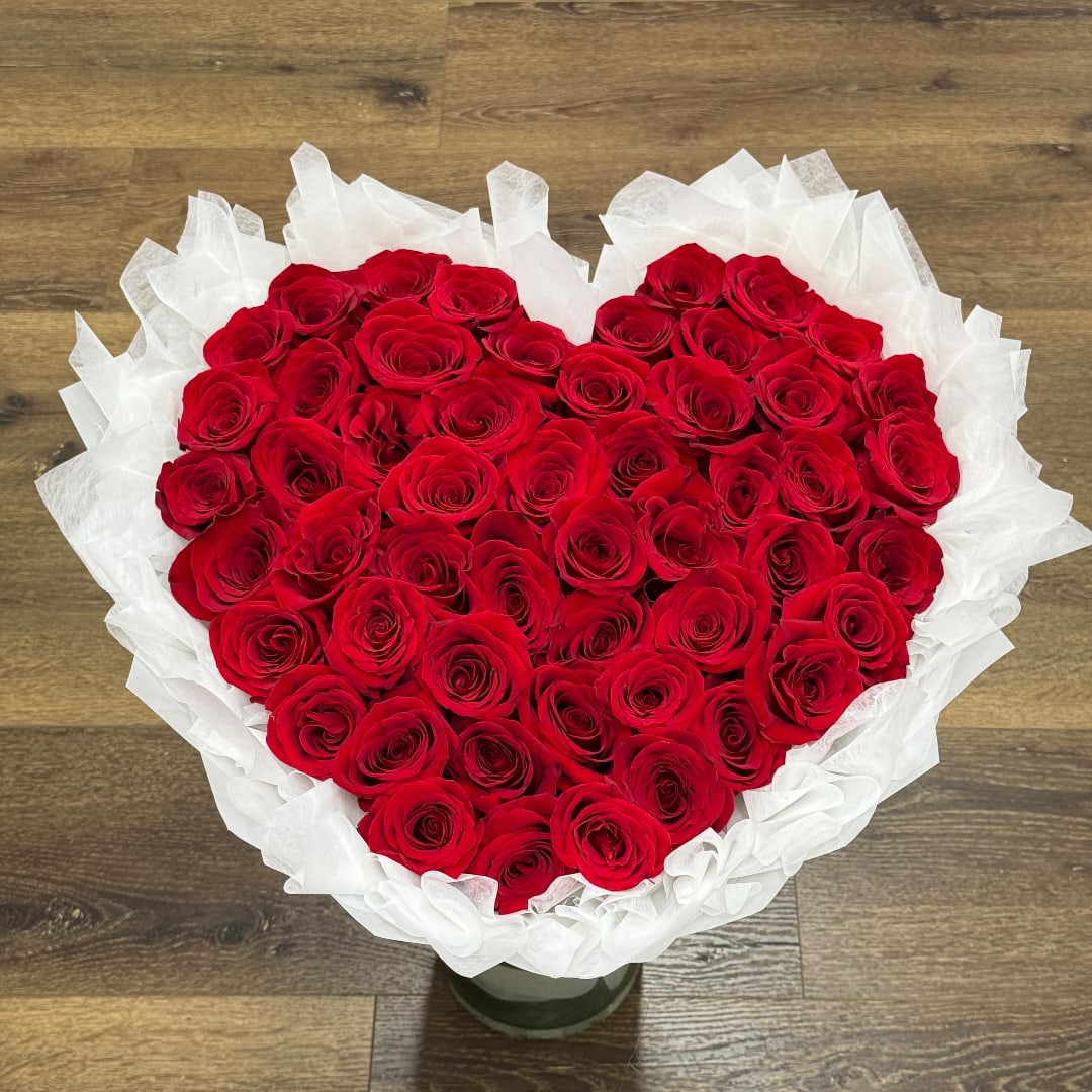 Heart-shaped bouquet of red roses wrapped in white paper