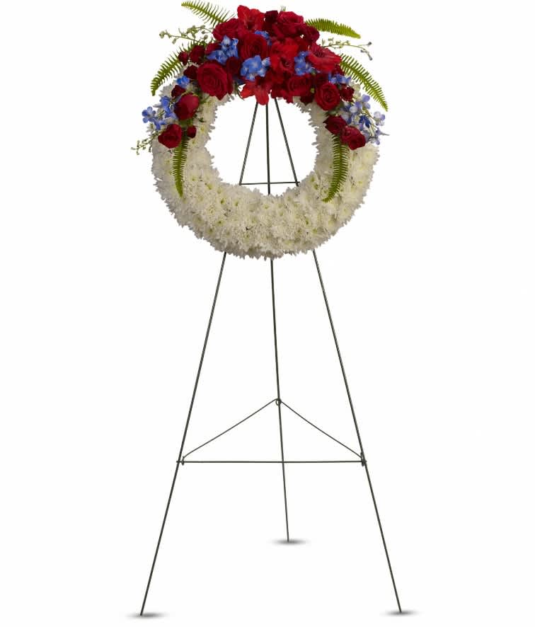 Reflections of Glory Wreath - A stunning display of patriotism, strength and sympathy. This red, white and blue wreath delivers a lovely message about the dignity of the deceased. A lovely array of flowers such as blue hydrangea, red roses and spray roses, delicate blue delphinium, red gladioli, white cushion spray chrysanthemums and more create a circle of serene beauty. Approximately 24 1/2" W x 24 1/2" H
