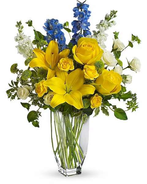 Yellow lilies and roses in a clear glass vase with blue and white flowers