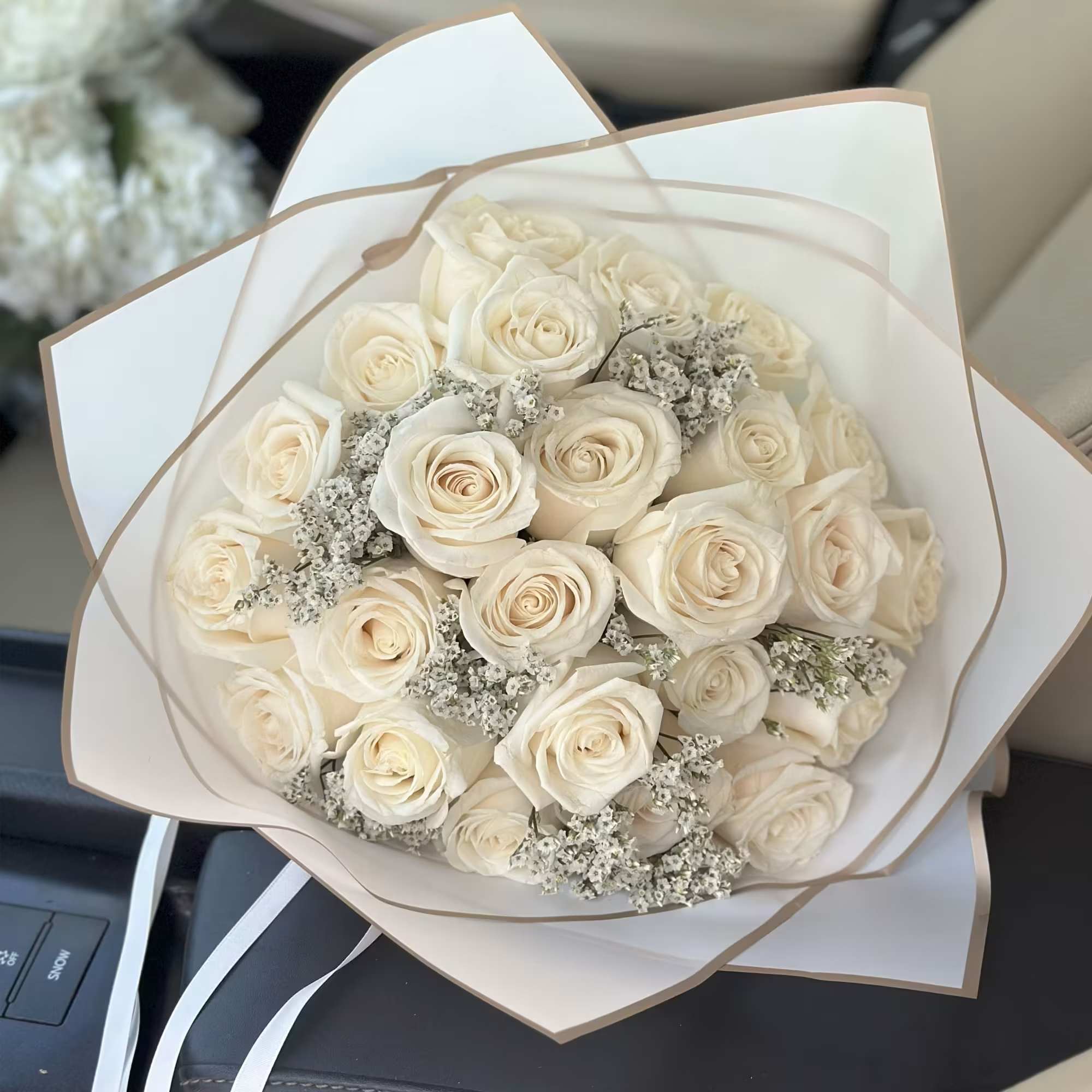 Bouquet of cream roses with small white filler flowers in white wrap