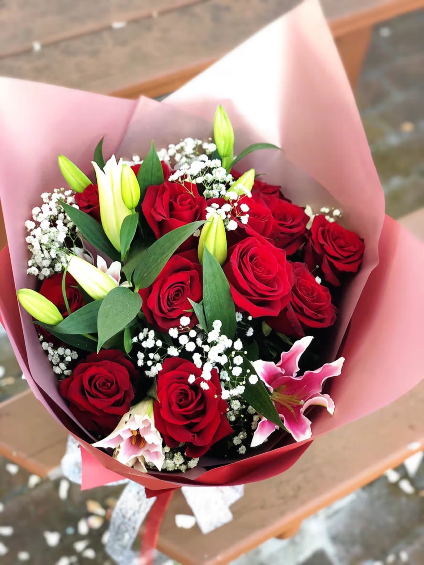 Bouquet of red roses and pink lilies wrapped in pink paper