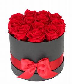Red roses arranged in a round black box with a red ribbon bow