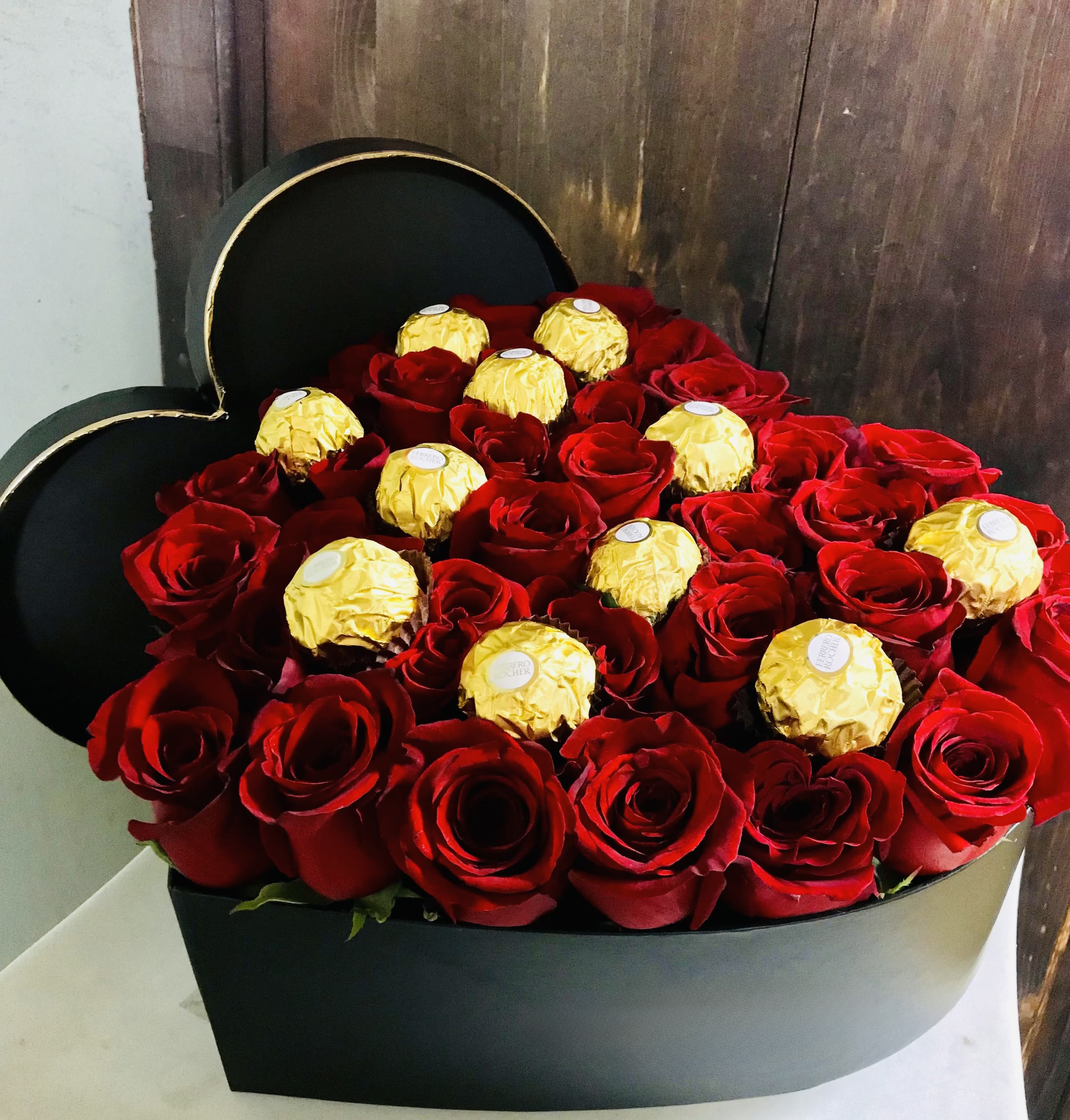 Heart-shaped box filled with red roses and gold-wrapped chocolates