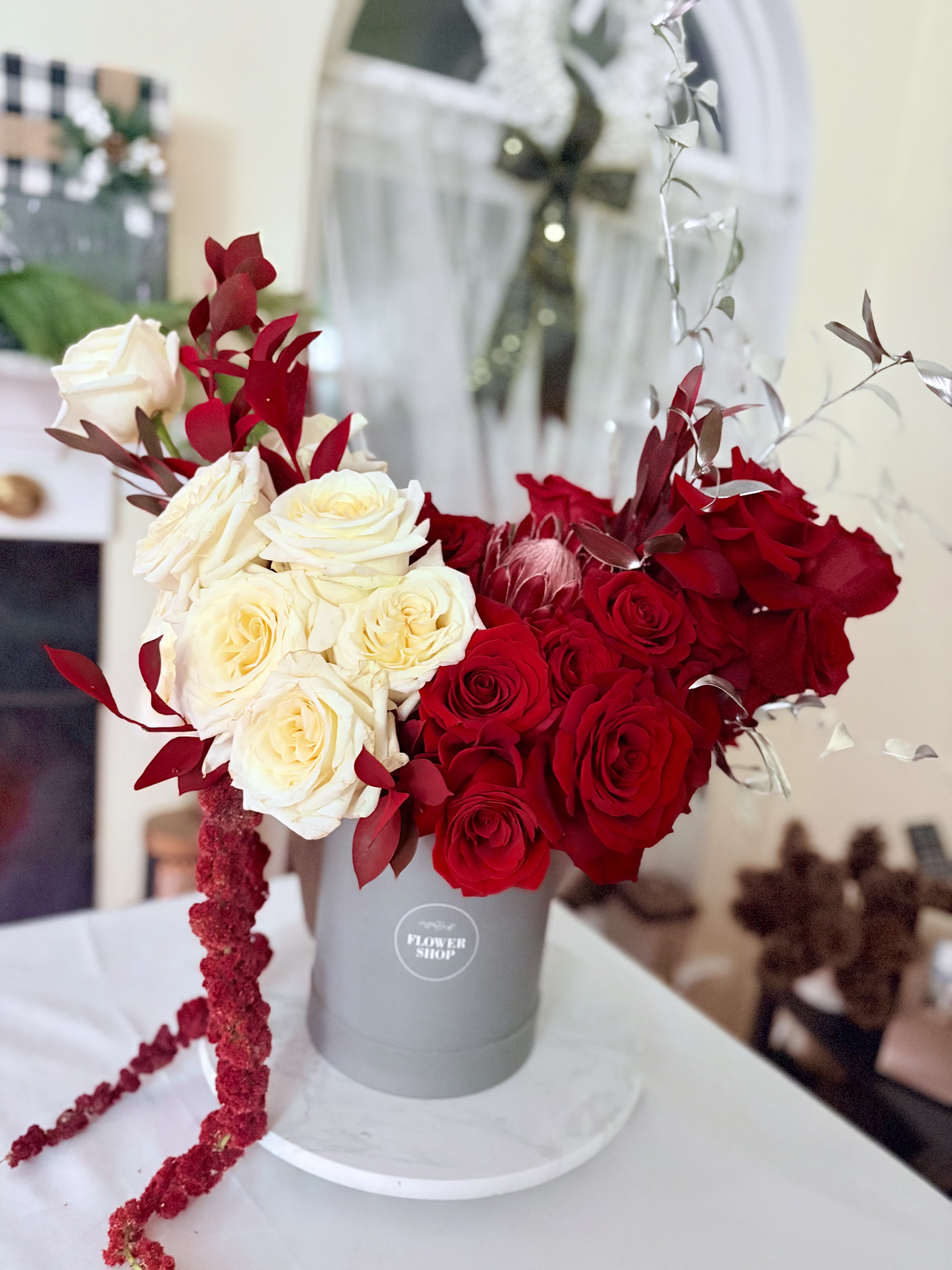Red and white roses arranged in a gray hat box