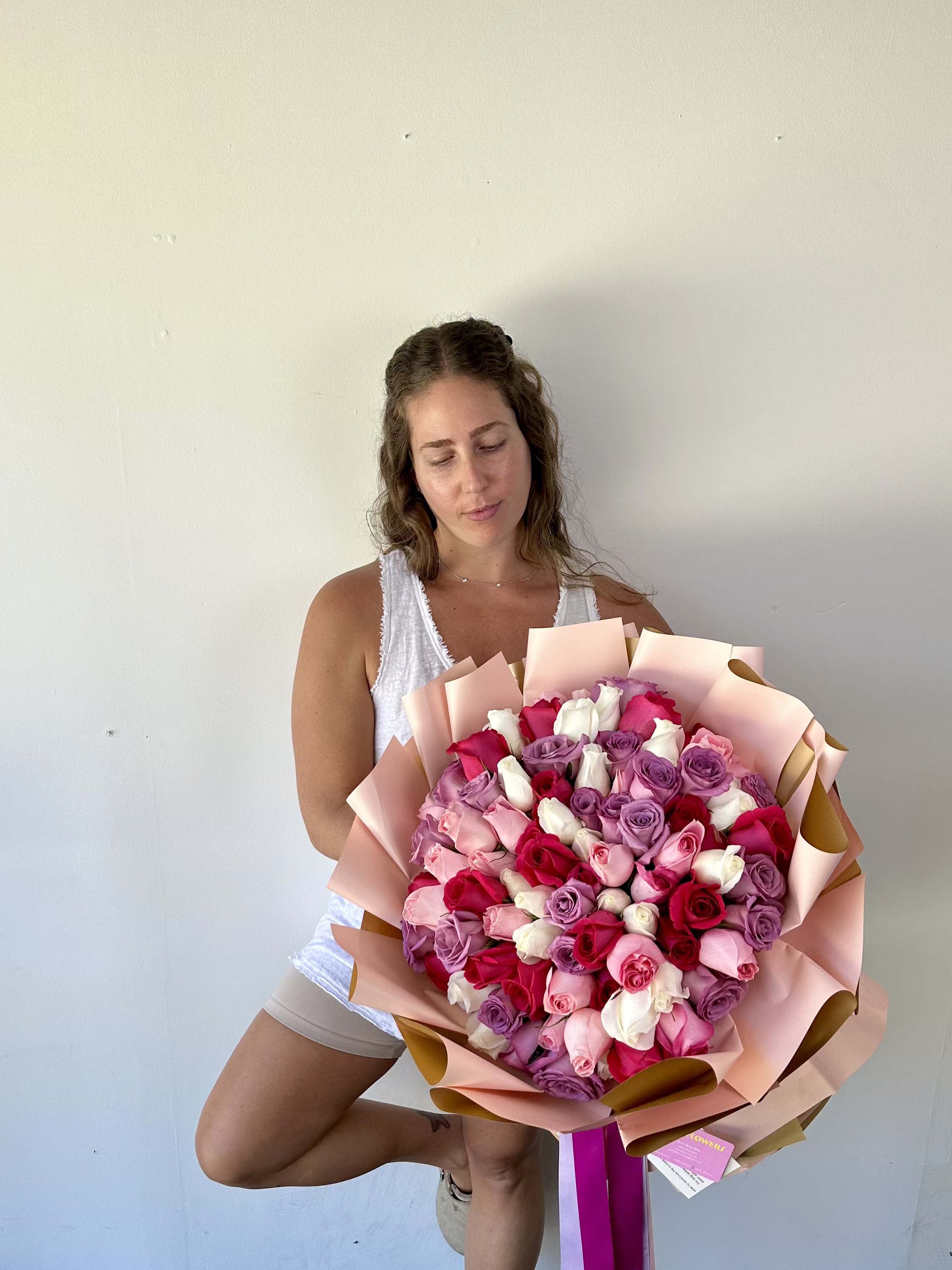 Woman holding a large bouquet of pink, red, white, and lavender roses