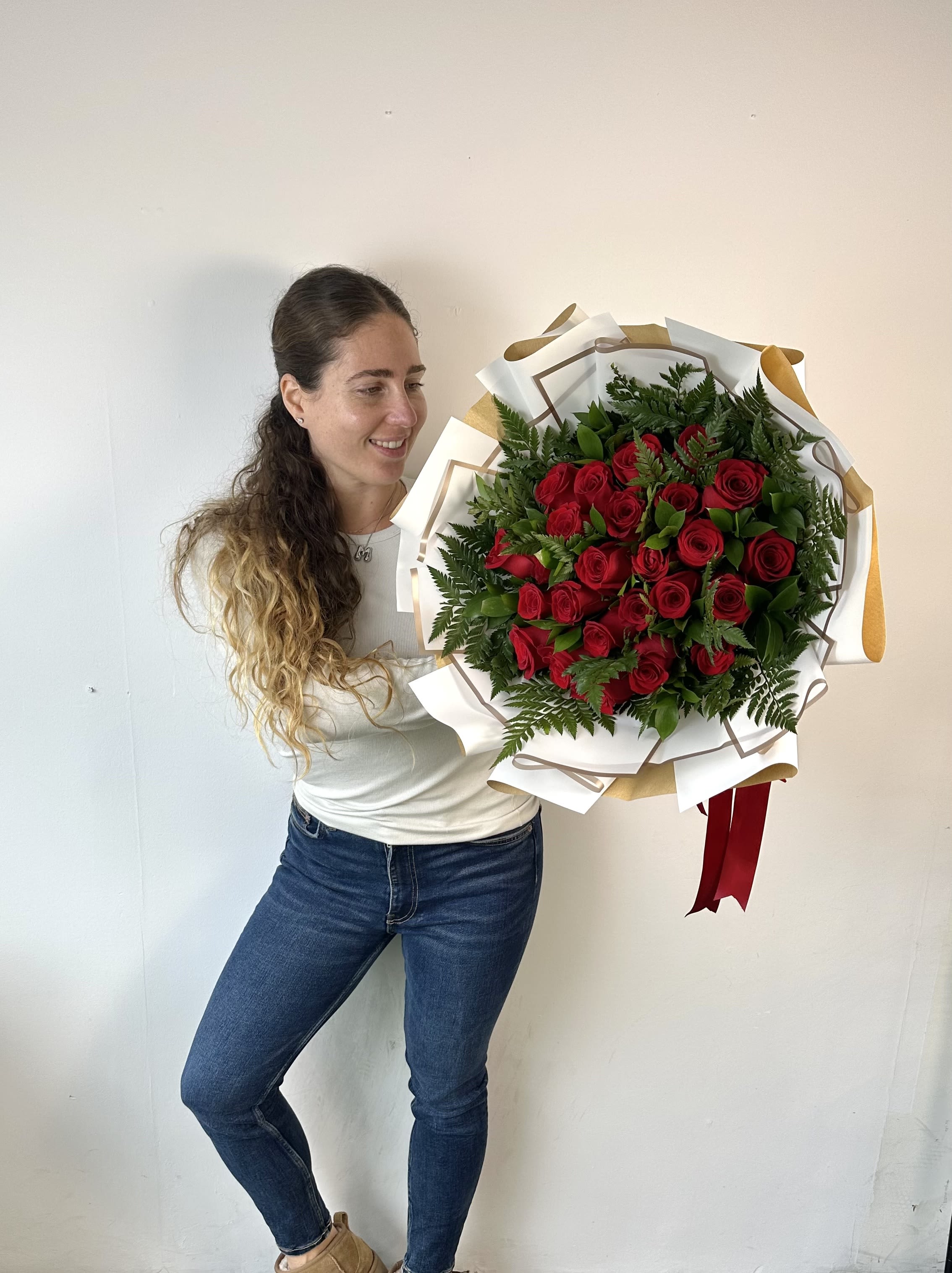 Woman holding a large bouquet of red roses wrapped in white paper