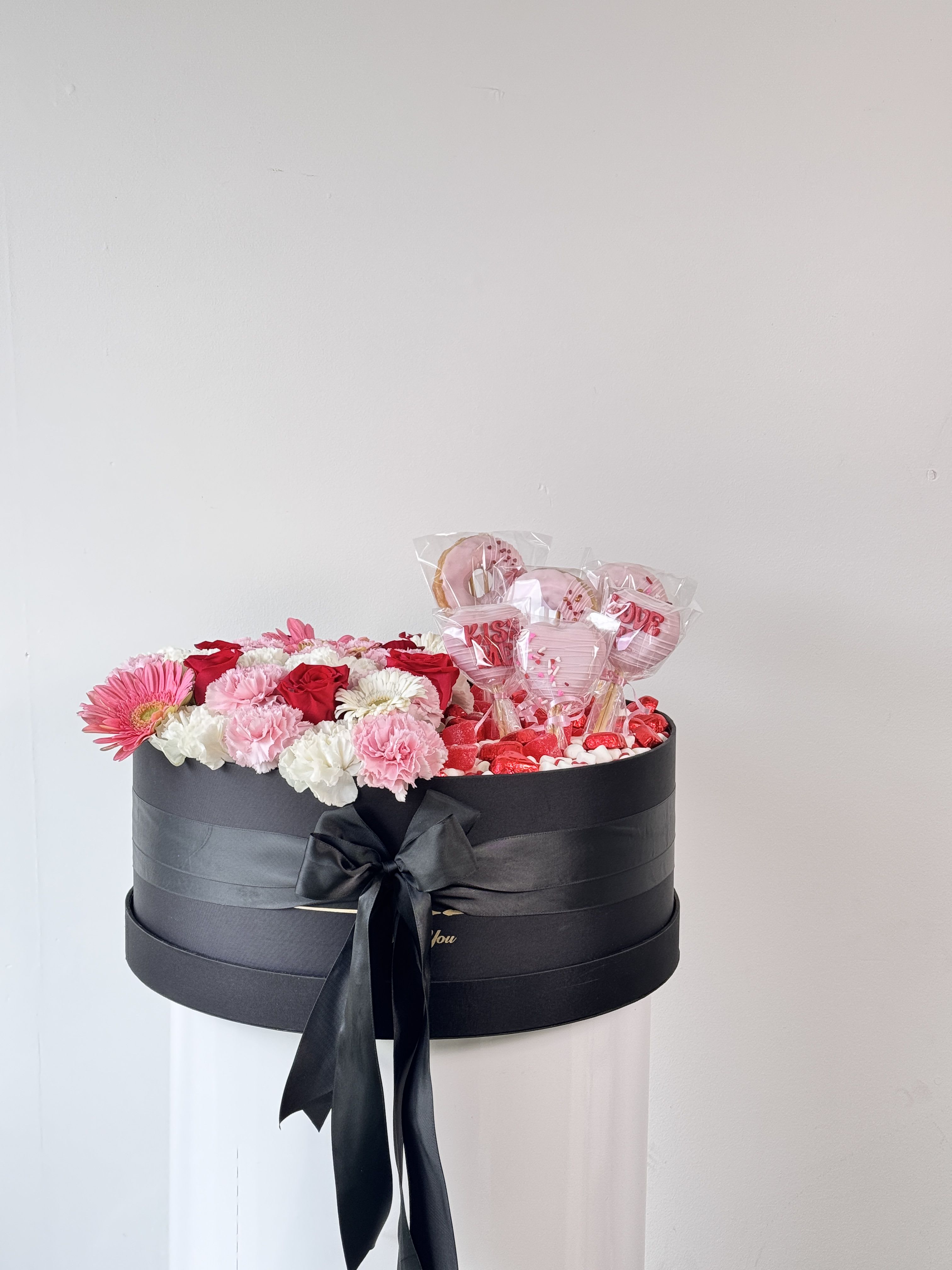 Black gift box with pink and white flowers and heart-shaped lollipops