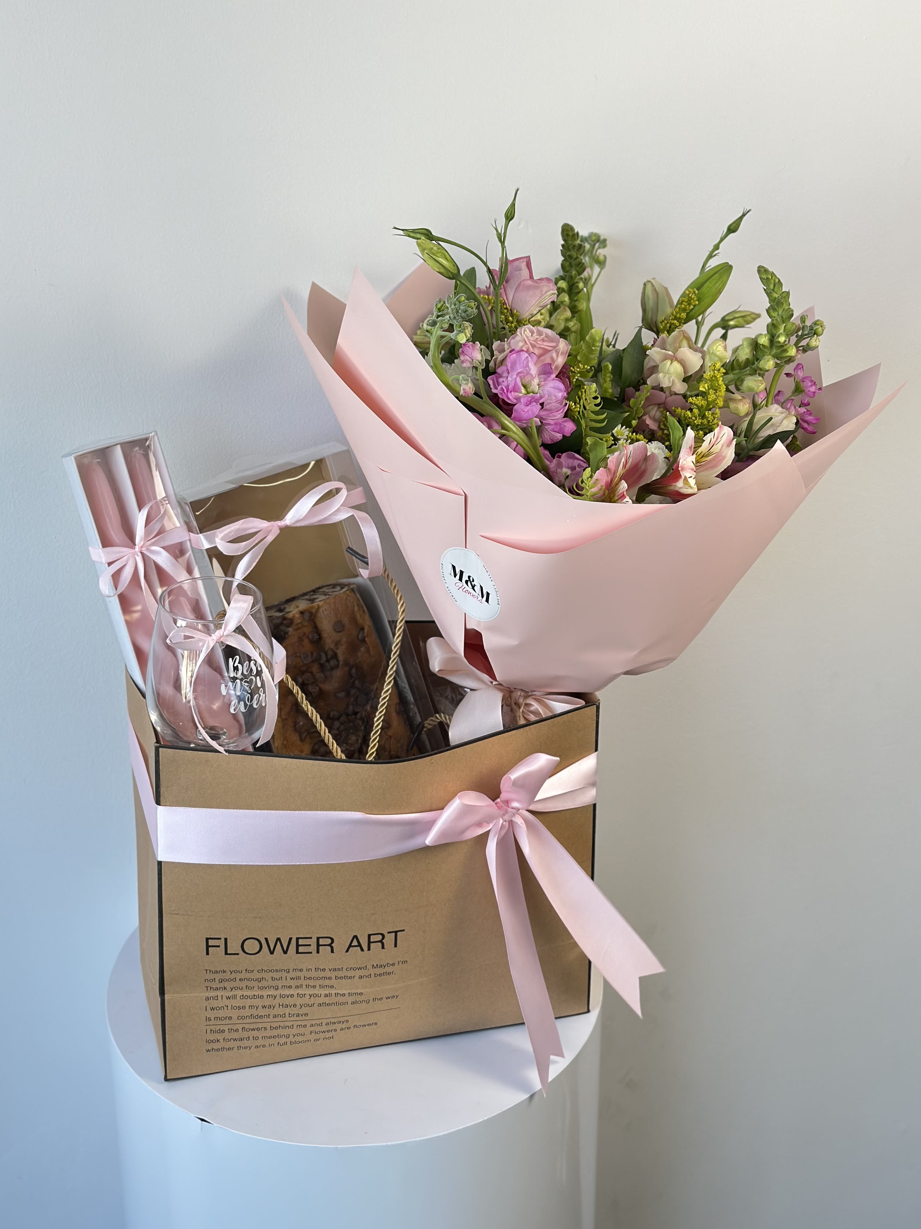 Pink bouquet in a gift box with a glass and baked treat