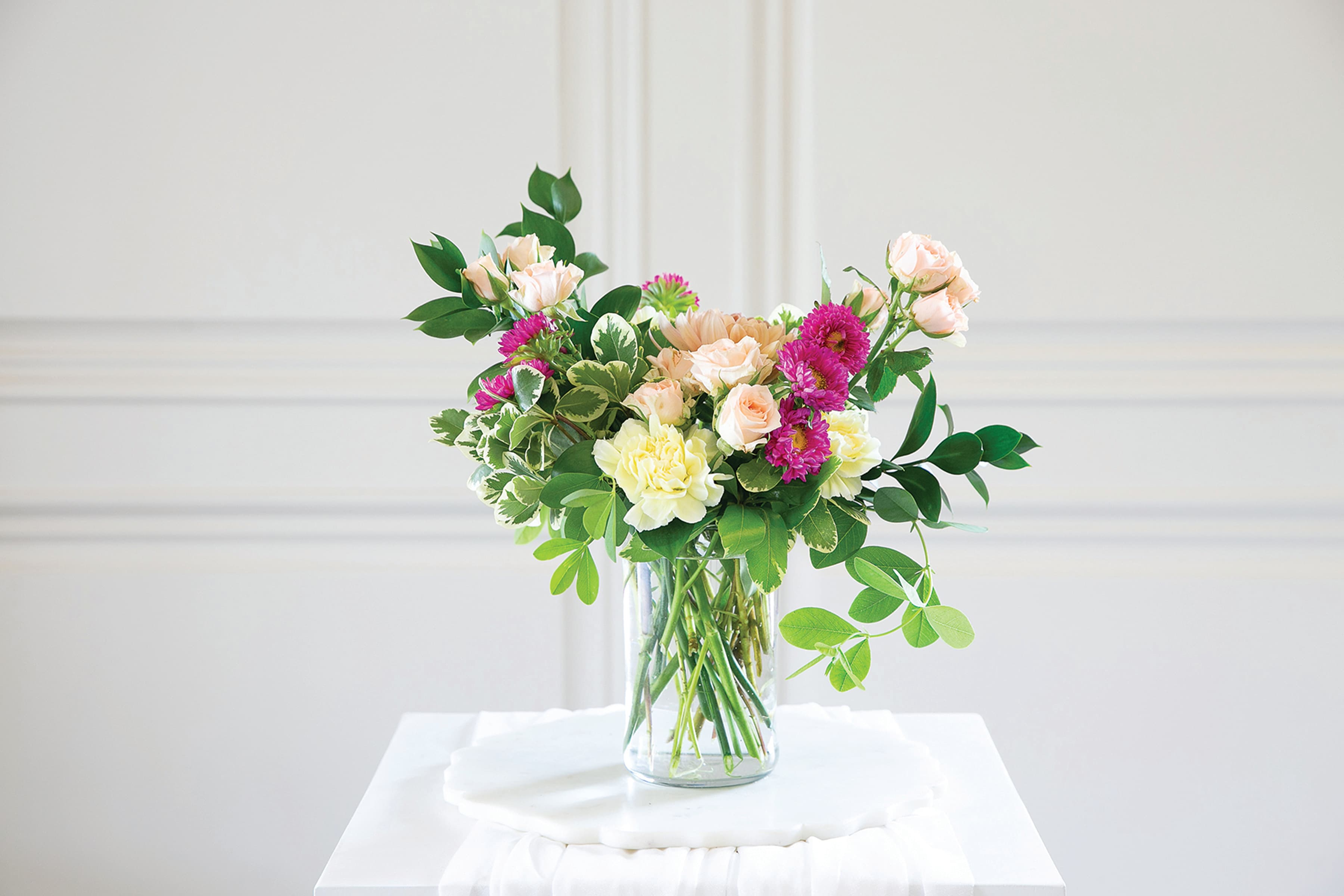 Mixed bouquet of pastel roses and chrysanthemums in a clear glass vase