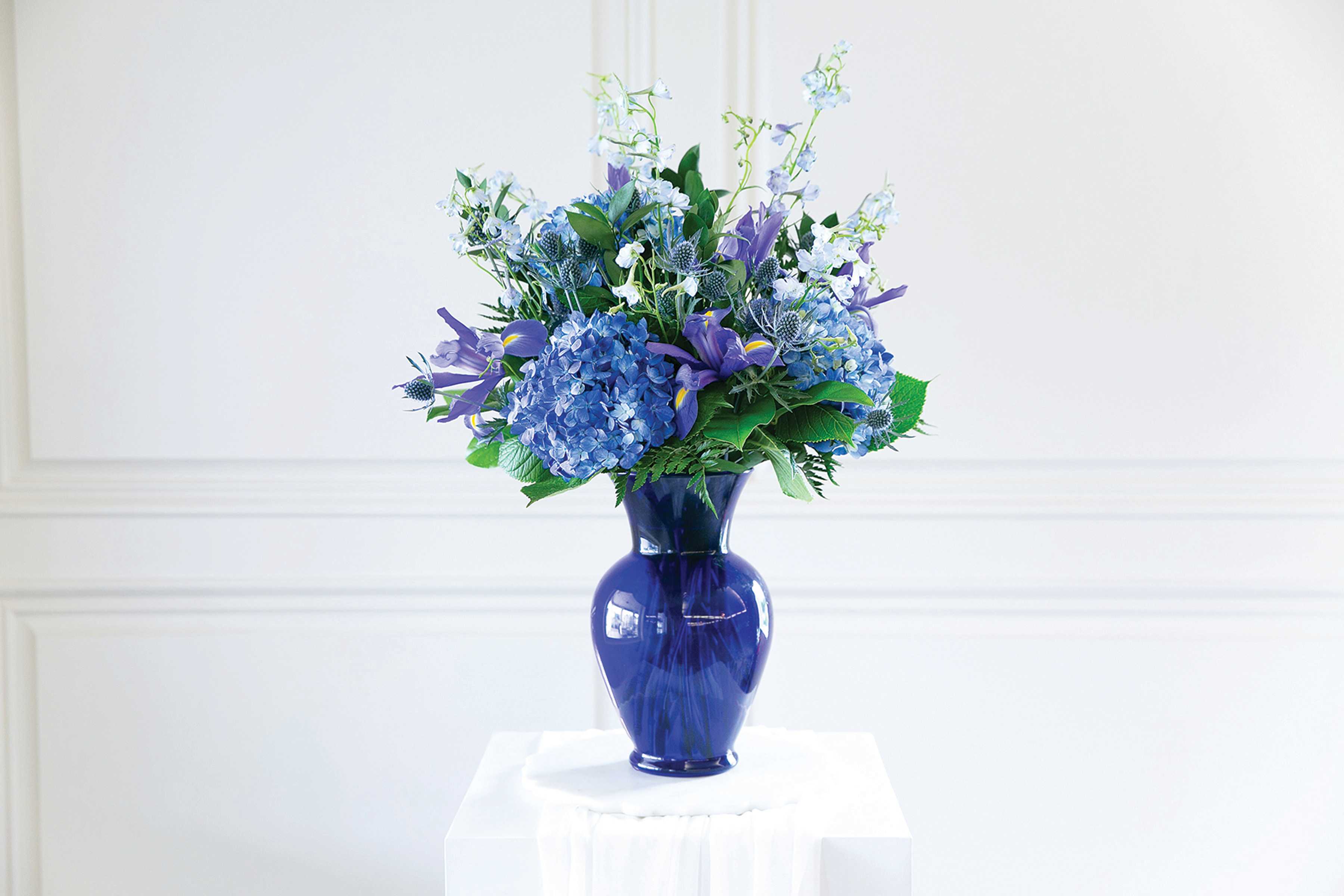 Blue and purple flower arrangement in a cobalt vase