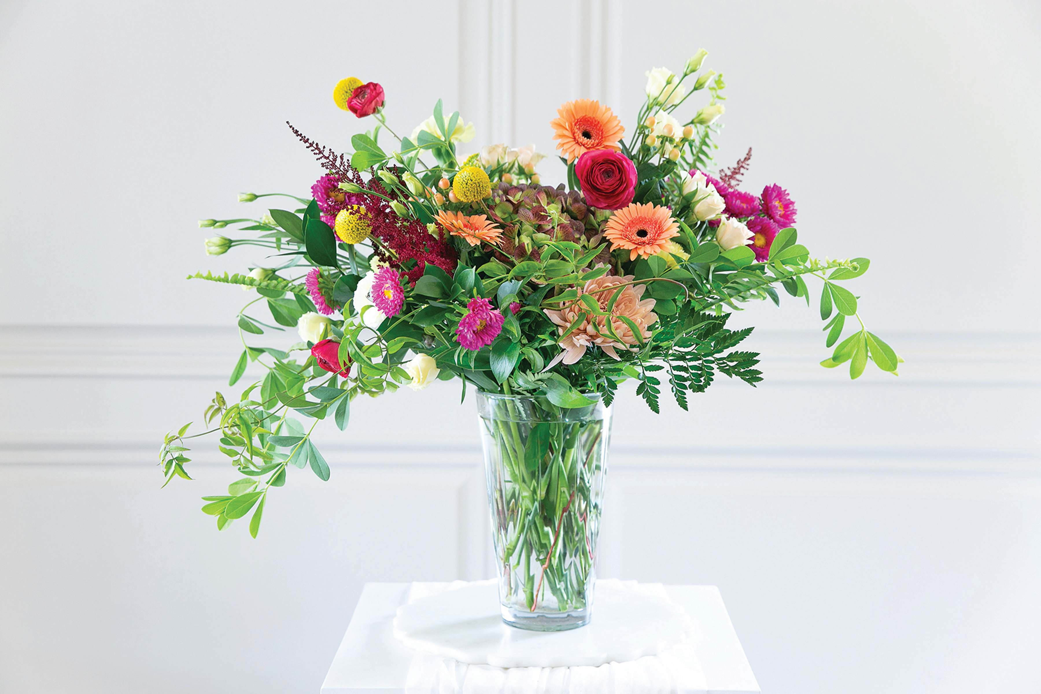 Mixed bouquet of bright flowers in a clear glass vase