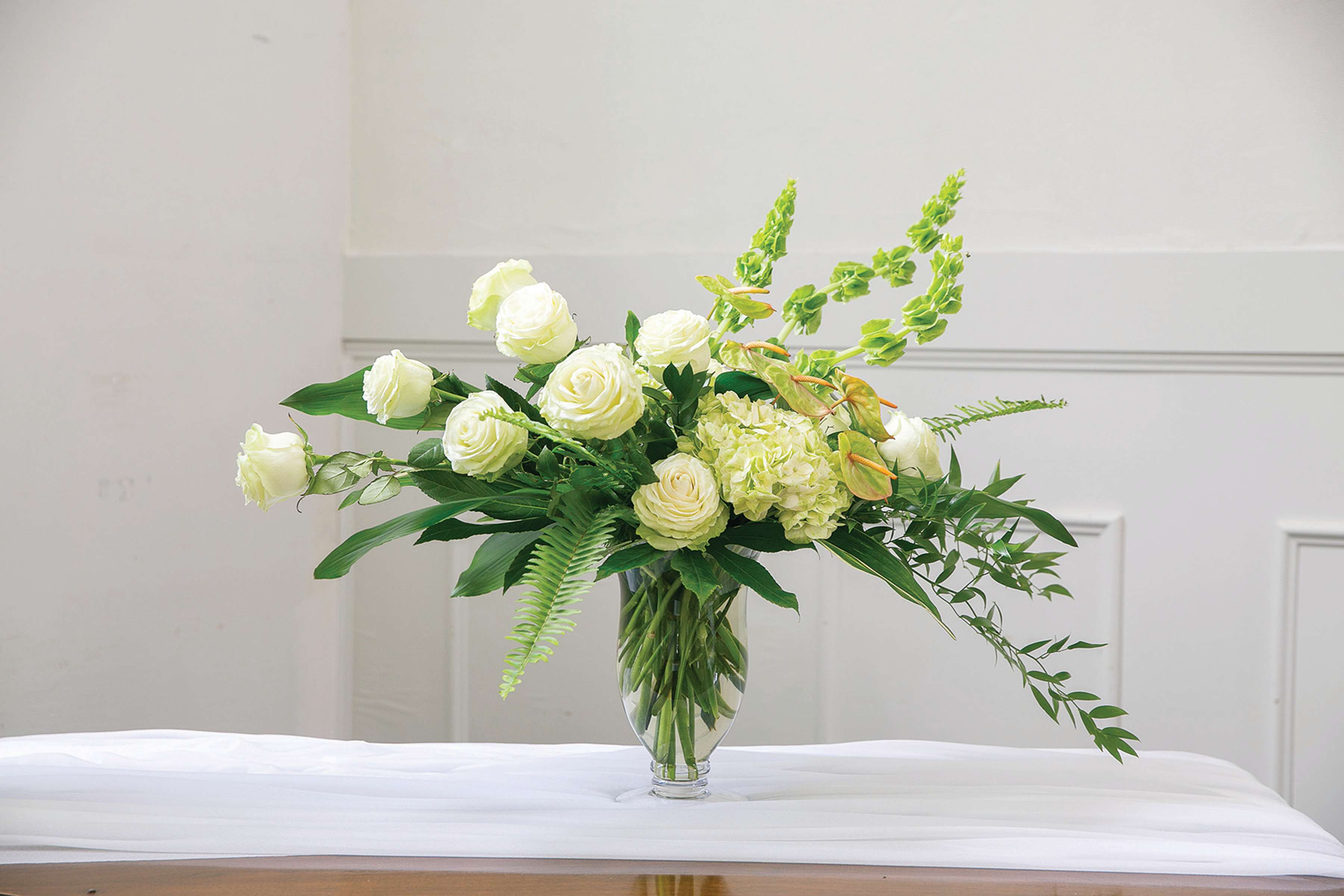 White roses and green flowers in a clear glass vase