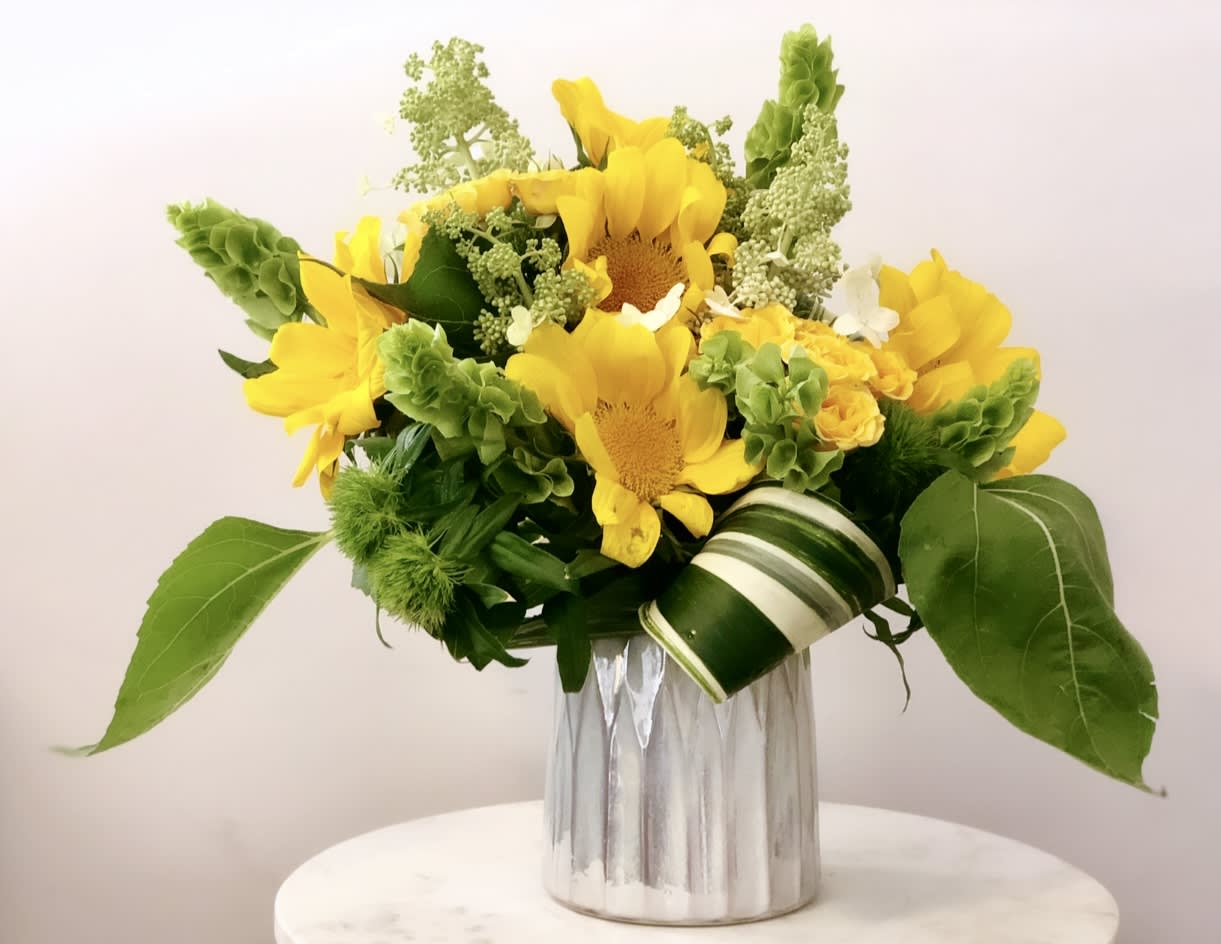 SUNFLOWER FIELDS - Bright, cheerful, and full of sunshine — Sunflower Fields is a stunning arrangement featuring a harmonious blend of vibrant sunflowers and bells of Ireland, artfully arranged to capture the essence of a sunny meadow. This bouquet brings a touch of warmth and joy to any setting.​  Ideal for birthdays, celebrations, or simply to brighten someone's day. A favorite among customers in San Diego, searching for sunflower arrangements, bright floral bouquets, or same-day flower delivery.