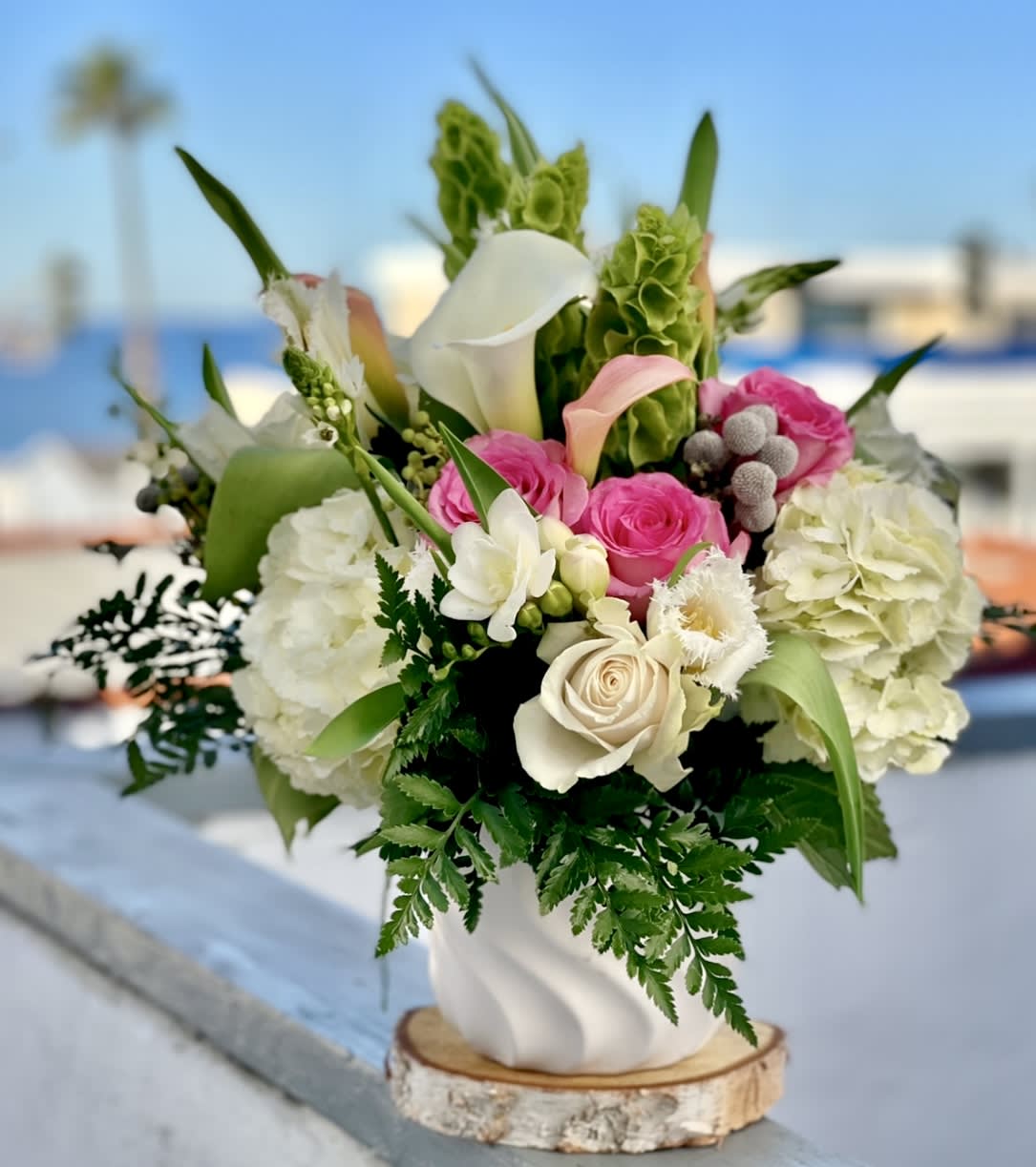 CALEY - Delicate, dreamy, and effortlessly feminine — Caley features a soft mix of blush garden roses, pale peach ranunculus, white calla lilies, and airy lisianthus, all accented with wispy greenery and styled in a soft-toned ceramic vase. A floral daydream in pastel.  Perfect for birthdays, new baby celebrations, or simply brightening someone’s day. Loved by customers in San Diego and North County searching for pastel flower arrangements, romantic bouquet delivery, or soft pink and peach florals near me with same-day service.
