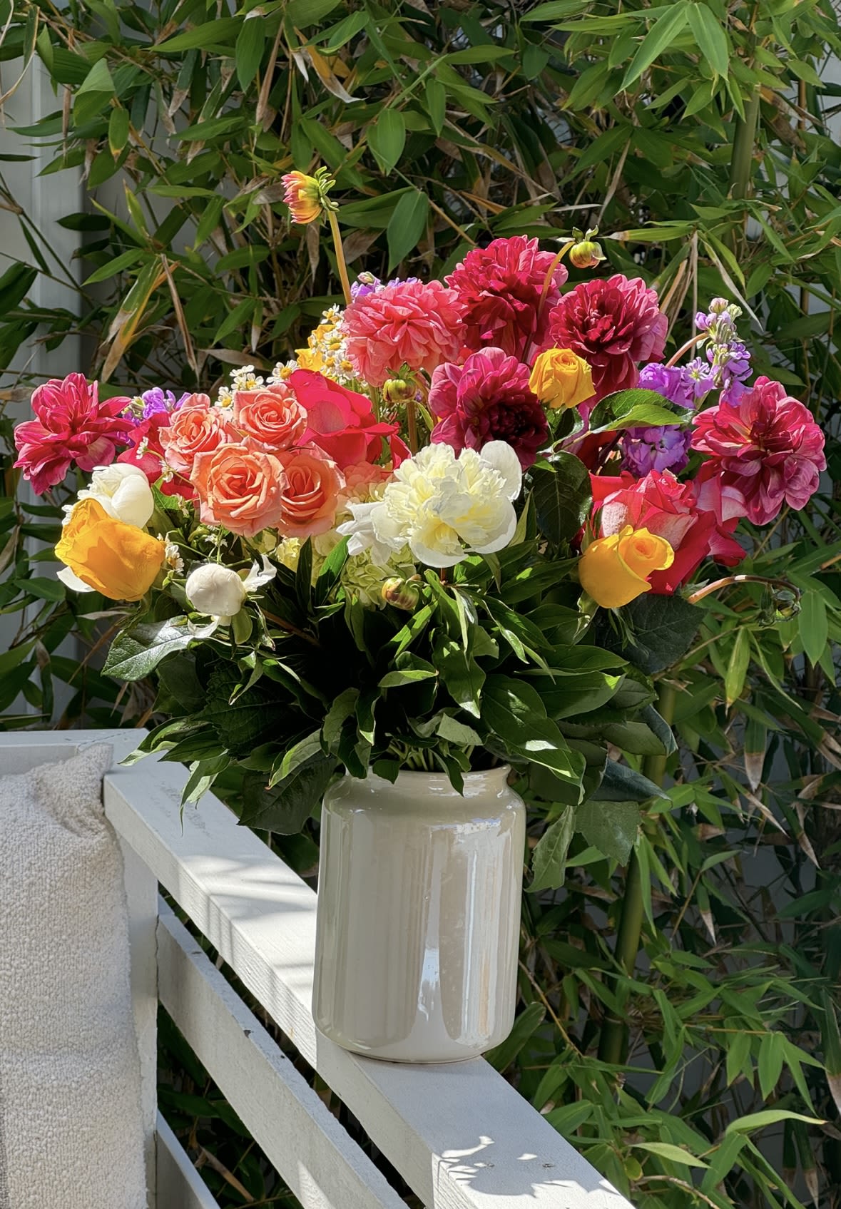 Bright mixed bouquet in a cream vase with pink, yellow, white, and purple blooms