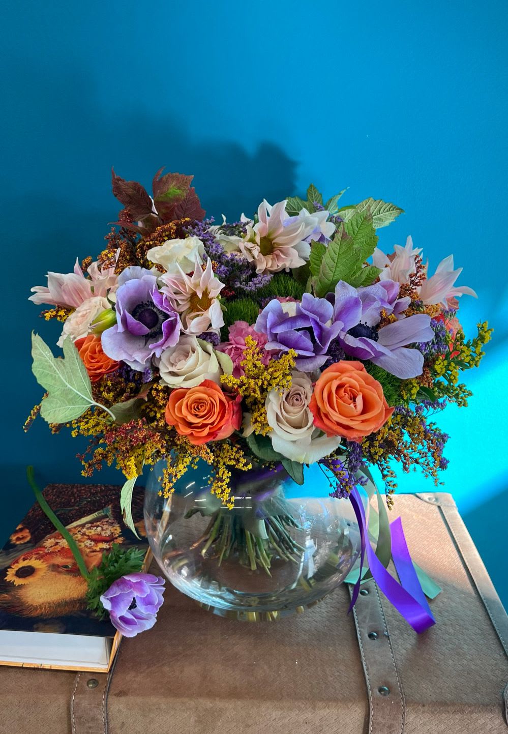 Mixed bouquet of purple, peach, and white flowers in a glass vase