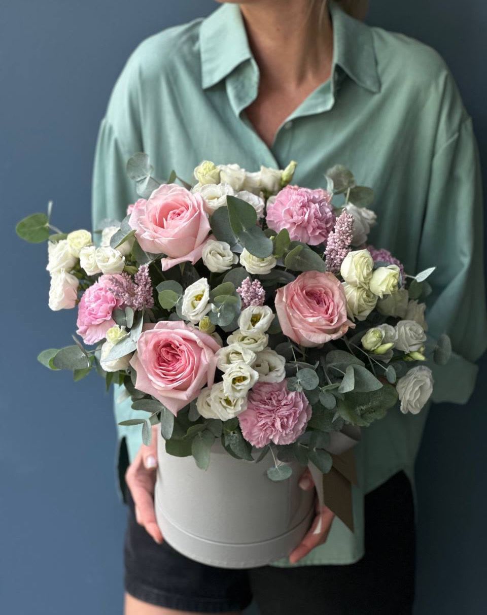 Pink and white flowers arranged in a round hatbox