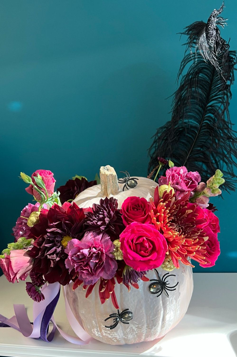 Floral arrangement in a white pumpkin with pink and burgundy blooms