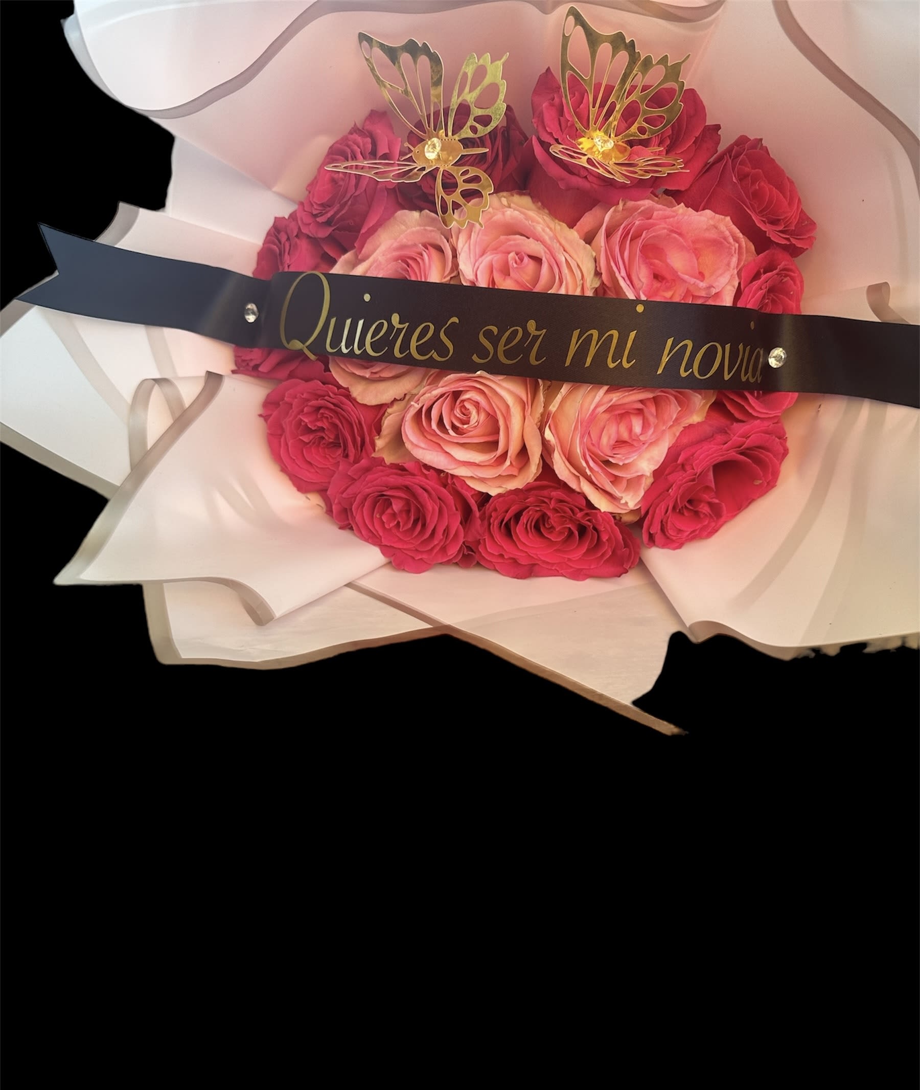 Pink and red rose bouquet wrapped in white paper with a black ribbon