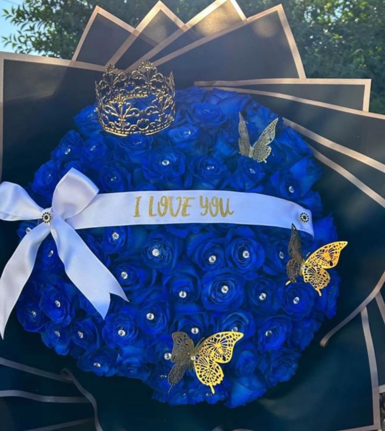 Blue rose bouquet with a white ribbon and decorative crown