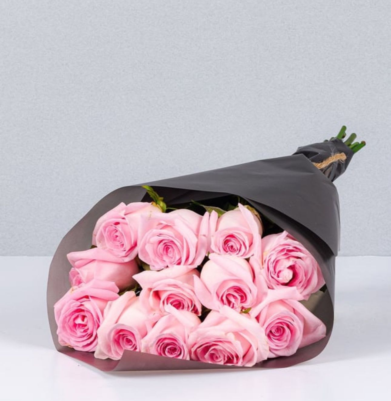 Bouquet of pink roses wrapped in dark paper