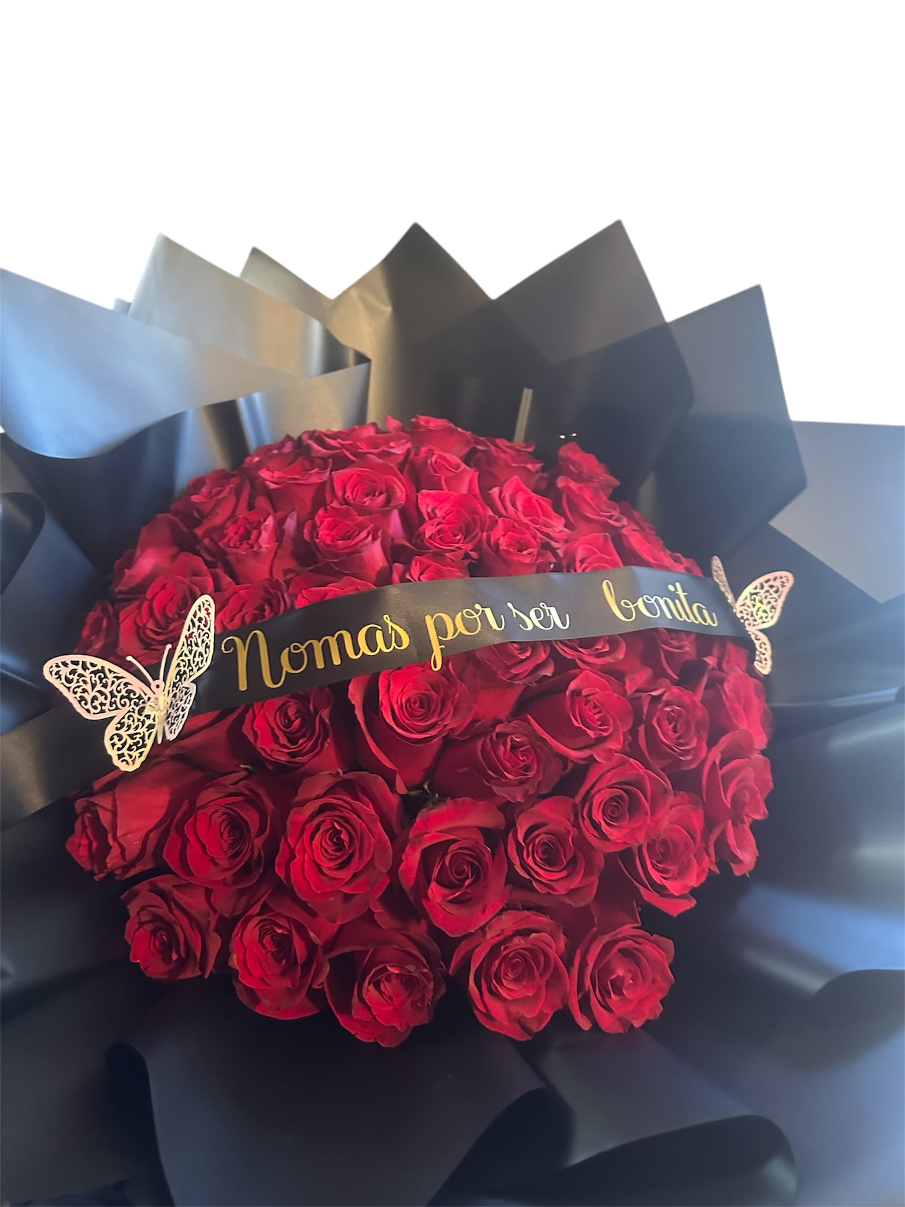 Bouquet of red roses wrapped in black paper with a gold ribbon