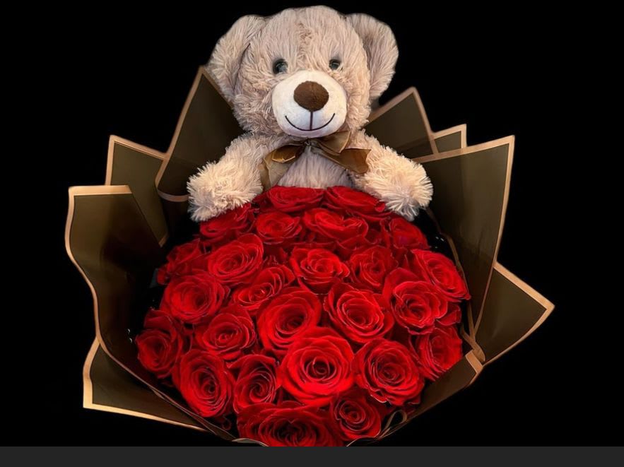 Teddy bear holding a bouquet of red roses