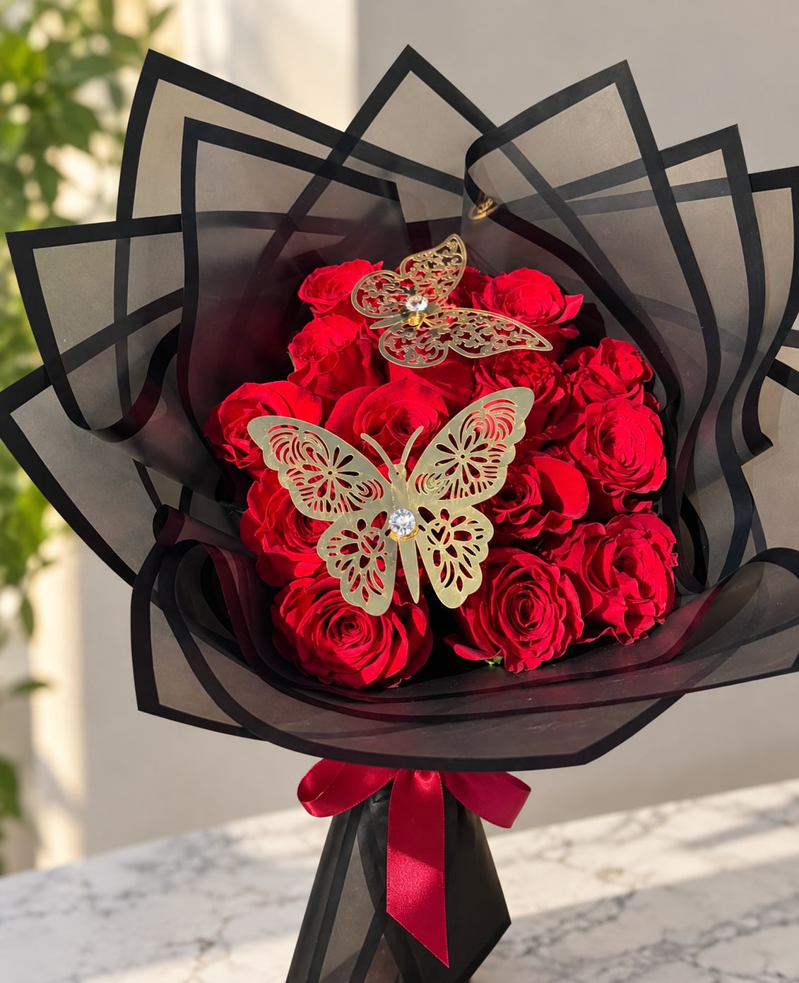 Bouquet of red roses wrapped in black paper with butterfly decorations