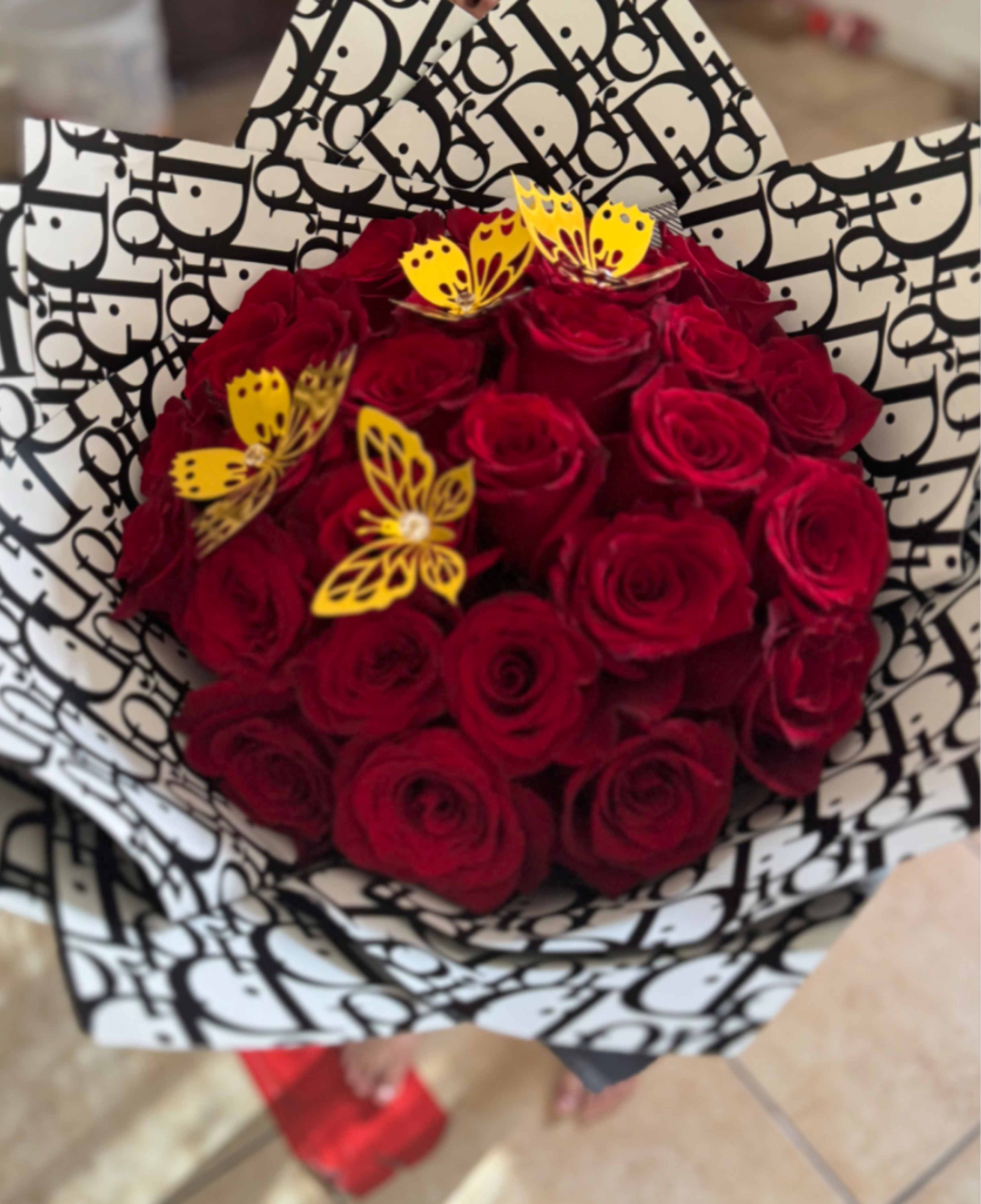 Bouquet of red roses wrapped in black-and-white patterned paper with yellow butterfly accents