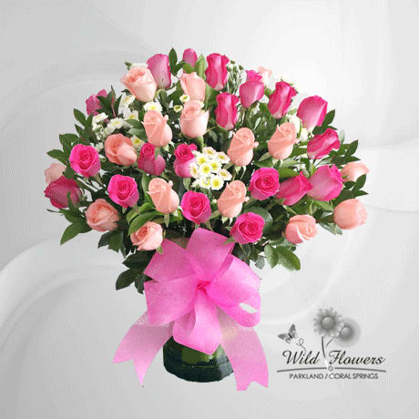 Bouquet of pink and peach roses in a vase with a pink ribbon
