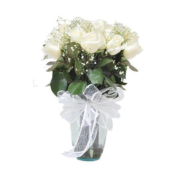 White rose bouquet in a glass vase with a white ribbon