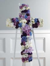 Floral cross arrangement in purple, blue, and white flowers on a stand