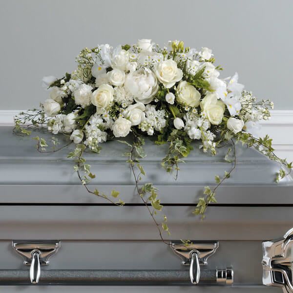 White floral casket spray with trailing greenery